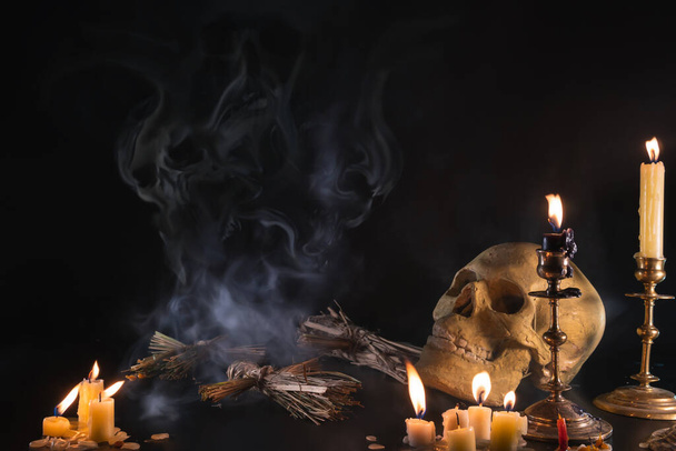Vecchio Teschio e candela con incenso sulla vecchia targhetta dell'altare che ha poca luce. Seleziona messa a fuoco, sfondo nero. Bambole vudù di paglia. Fumo misterioso, terribile del male - Foto, immagini