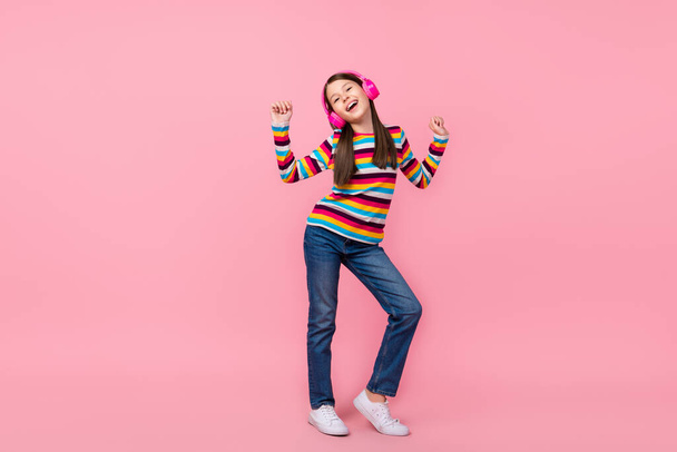 Photo of dreamy inspired little lady dance wear earphones striped shirt jeans shoes isolated pink color background - Foto, Bild