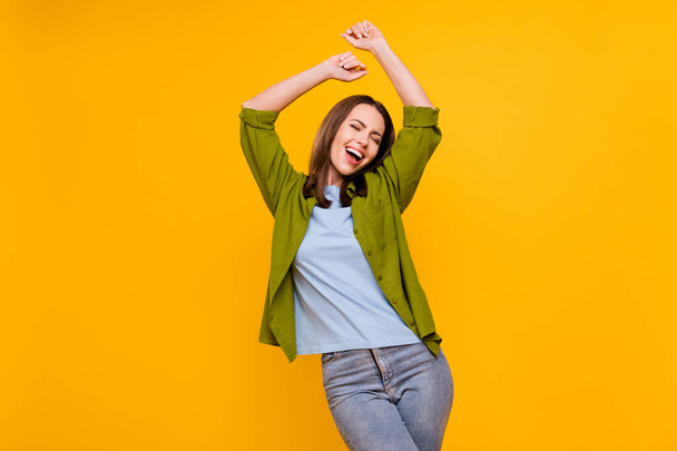 Photo of lucky sweet young lady wear green shirt smiling dancing isolated yellow color background - Valokuva, kuva