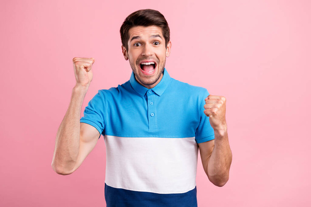 Photo of young excited smiling good mood guy raise fists in victory triumph isolated on pink color background - Foto, imagen
