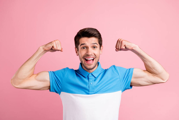 Portrait of young good mood excited male showing muscles fit body superhero isolated on pink color background - Foto, Imagem