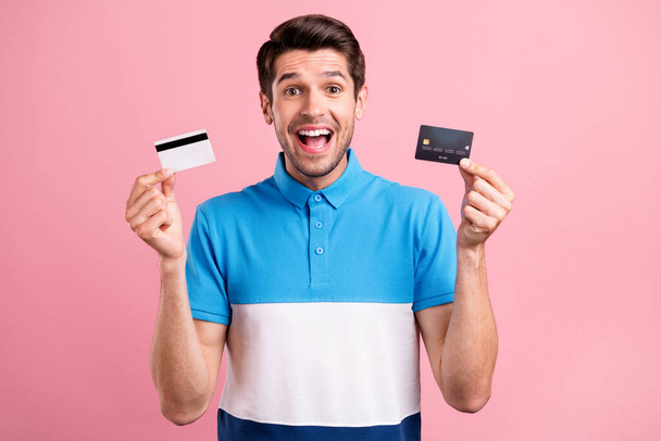 Photo of joyful brunet young guy hold card wear striped t-shirt isolated on pink color background - Foto, Imagem