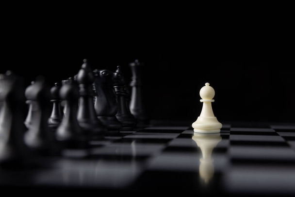 ビジネスコンセプトのボード上の黒い部分の多くとの単一の白いチェスの戦い、戦術とデザインの役割の再生 - 写真・画像