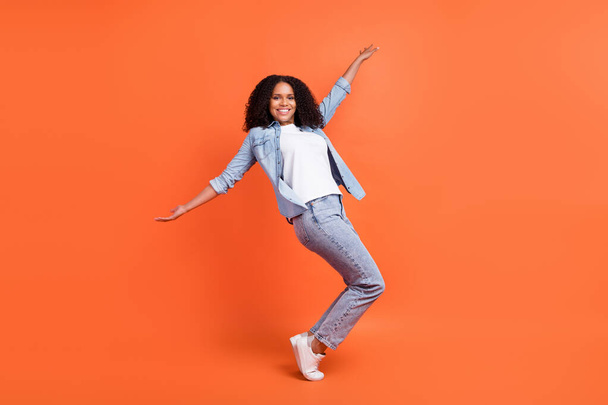 Full length photo of funky millennial brunette lady dance wear jeans shirt shoes isolated on orange background - Foto, immagini