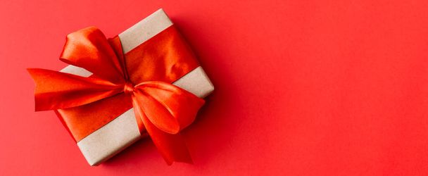 Banner made of Present box with red bow on red background. Flat lay, top view, copy space - Photo, Image
