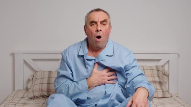 An elderly man in bed suffers from severe pain. Home sickness concept - Footage, Video