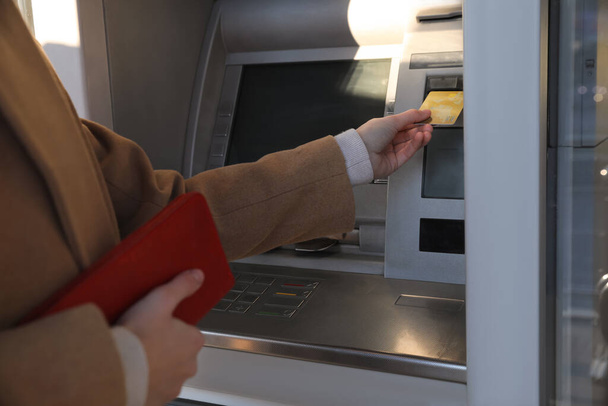 Young woman using cash machine for money withdrawal outdoors, closeup - 写真・画像