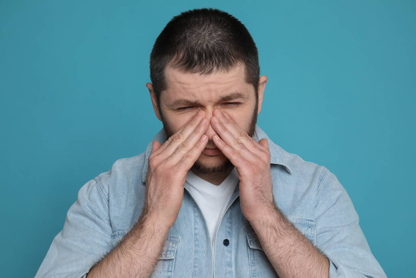 Man suffering from headache on light blue background - Photo, image