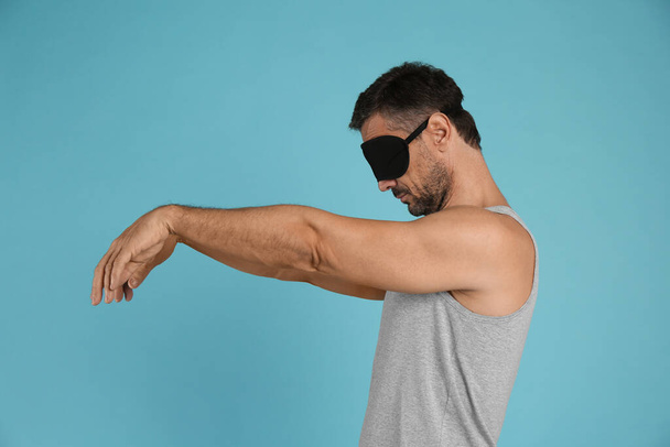 Man with eye mask in sleepwalking state on light blue background - Foto, immagini