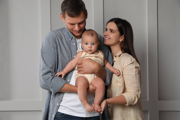 Happy family. Couple with their cute baby near light wall - Foto, immagini