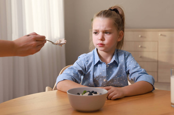 Cute little girl refusing to eat her breakfast at home - Foto, Imagen
