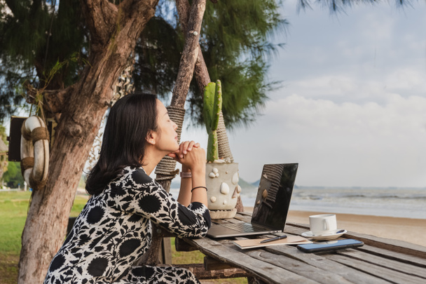 Деловая женщина расслабляет дыхание свежим воздухом во время работы с компьютером на пляже. - Фото, изображение