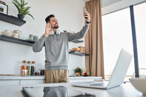 Man waving and attentively looking at the smartphone screen while having video call - Photo, image