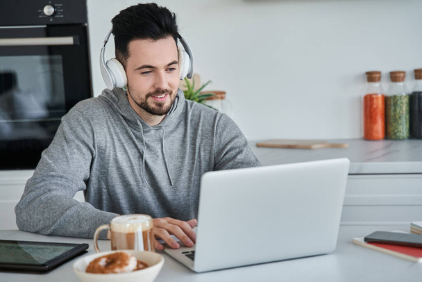 Mężczyzna noszący słuchawki podczas rozmowy wideo na laptopie podczas zdalnej pracy - Zdjęcie, obraz