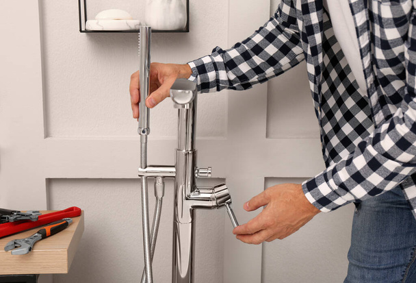 Man installing water tap with shower head in bathroom, closeup - Photo, Image