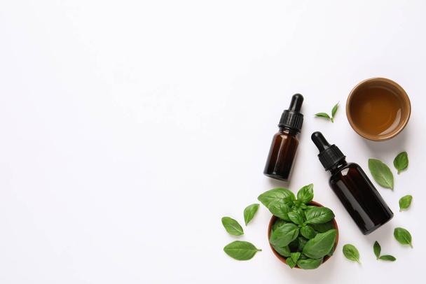 Essential basil oil with fresh leaves on white background, flat lay. Space for text - Photo, Image