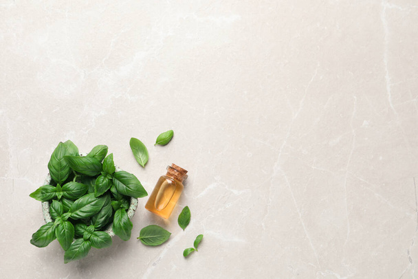 Bottle of essential basil oil and fresh leaves on light marble table, flat lay. Space for text - Foto, afbeelding