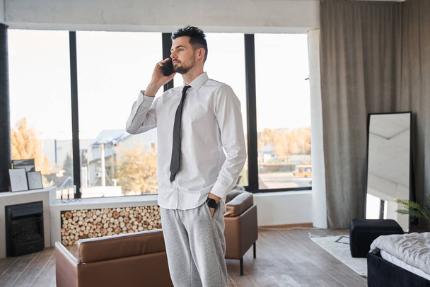 Businessman standing at his apartments and having conversation at the mobile phone - Φωτογραφία, εικόνα