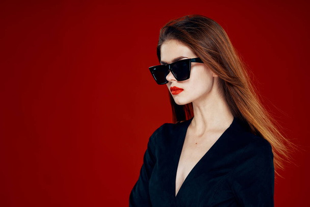 cheerful fashionable woman wearing sunglasses red lips posing red background - Фото, зображення