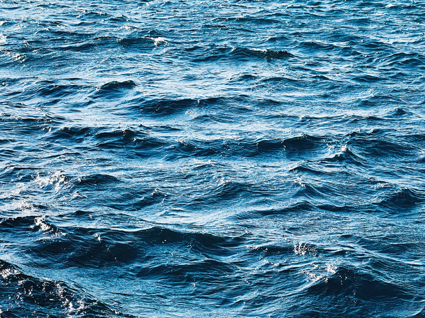 Zee, textuur en kust natuur concept. Blauwe oceaan water als achtergrond, vloeiende golven en zomervakantie reizen - Foto, afbeelding