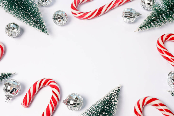 Різдвяна рамка з ялинками, цукерками та диско-кулями на білому тлі, вітальна листівка з місцем для тексту
 - Фото, зображення