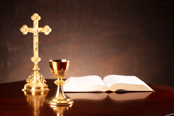 Catholic religion concept. The Cross,  Holy Bible and golden chalice on the altar.  - Photo, Image