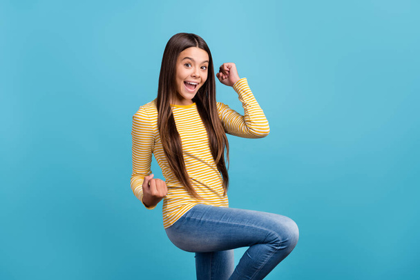 Photo of young excited girl celebrate victory triumph success fists hands isolated over blue color background - Fotoğraf, Görsel