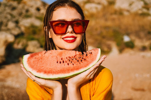 woman on the beach near the ocean eating watermelon - Фото, изображение