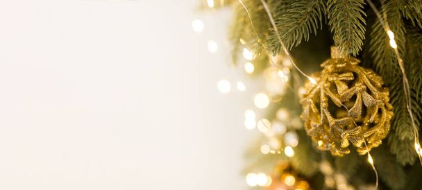 緑黄色のクリスマスツリー上の金のボールのおもちゃとガーランドの閉鎖 - 写真・画像