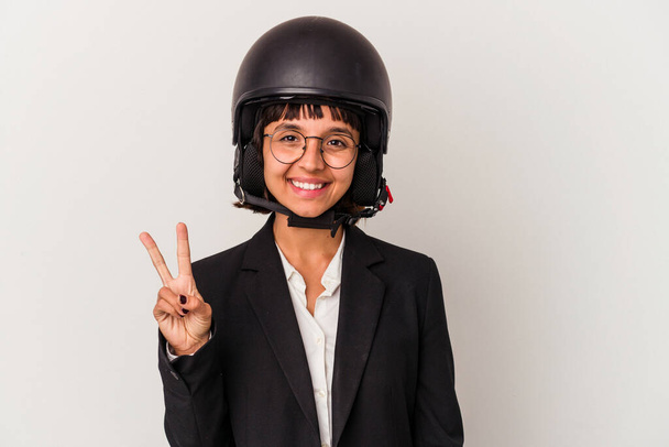 Joven mujer de negocios de raza mixta con un casco de moto aislado mostrando el número dos con los dedos. - Foto, imagen