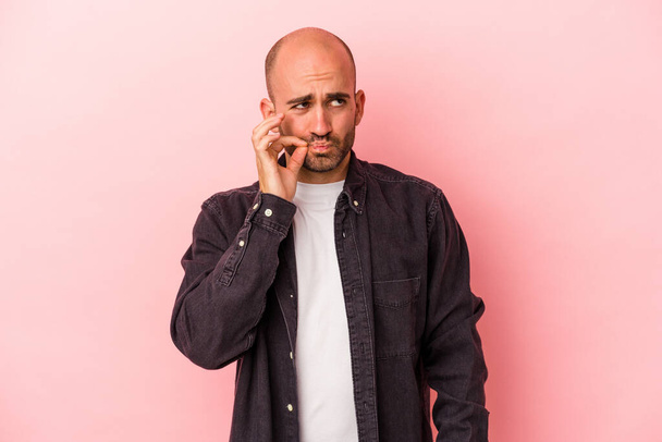 Young caucasian bald man isolated on pink background  with fingers on lips keeping a secret. - Valokuva, kuva