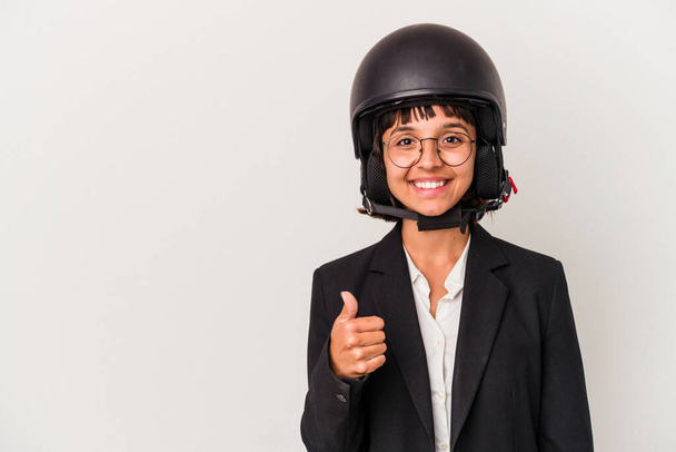 Joven mujer de negocios de raza mixta con un casco de moto aislado sonriendo y levantando el pulgar hacia arriba - Foto, imagen