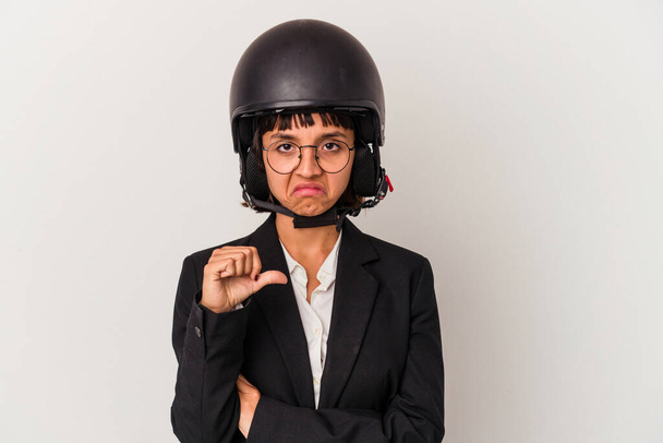 Joven mujer de negocios mixta que lleva un casco de moto aislado mostrando un gesto de aversión, pulgares hacia abajo. Concepto de desacuerdo. - Foto, imagen