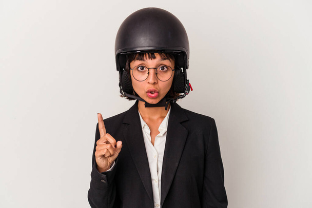Joven mujer de negocios de raza mixta con un casco de moto aislado que tiene una gran idea, concepto de creatividad. - Foto, imagen