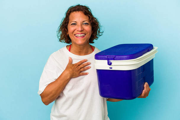 Middle age latin woman isolated on blue background laughs out loudly keeping hand on chest. - Photo, Image