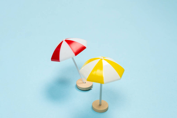 Żółto-czerwony parasol na niebieskim tle. Przestrzeń kopiowania. - Zdjęcie, obraz