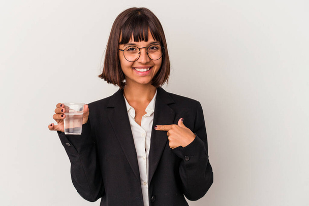 Young mixed race business woman holding a glass of water isolated on white background person pointing by hand to a shirt copy space, proud and confident - Photo, Image