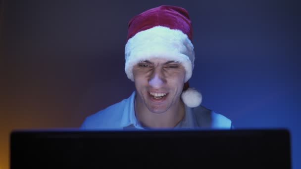 Happy man in de kerstman hoed glimlacht en communiceert op video bellen met behulp van laptop - Video