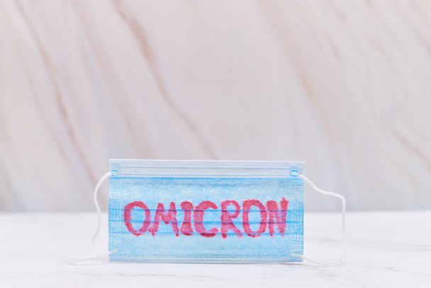 a face mask with - Omicron variant text on it. Covid-19 new variant - Фото, изображение