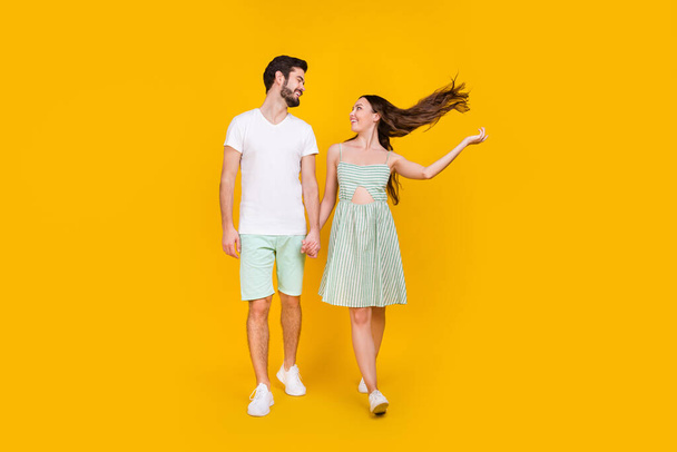 Photo of inspired couple in love hold hands enjoy promenade walk wear casual outfit isolated yellow color background - Foto, immagini