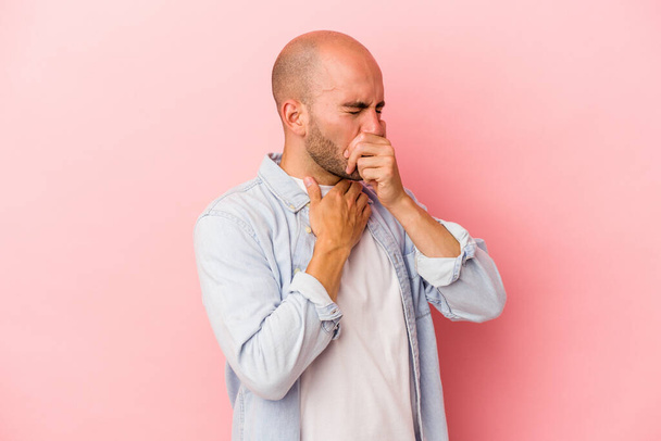Νεαρός καυκάσιος φαλακρός άνδρας απομονωμένος σε ροζ φόντο υποφέρει από πόνο στο λαιμό λόγω ιού ή λοίμωξης. - Φωτογραφία, εικόνα