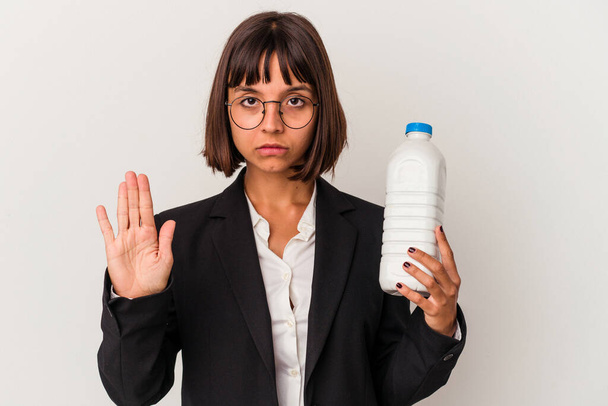 Young mixed race business woman holding a milk bottle isolated on white background standing with outstretched hand showing stop sign, preventing you. - Photo, image
