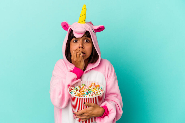 Mladá smíšená rasa žena nosí jednorožec pyžama jíst popcorn - Fotografie, Obrázek