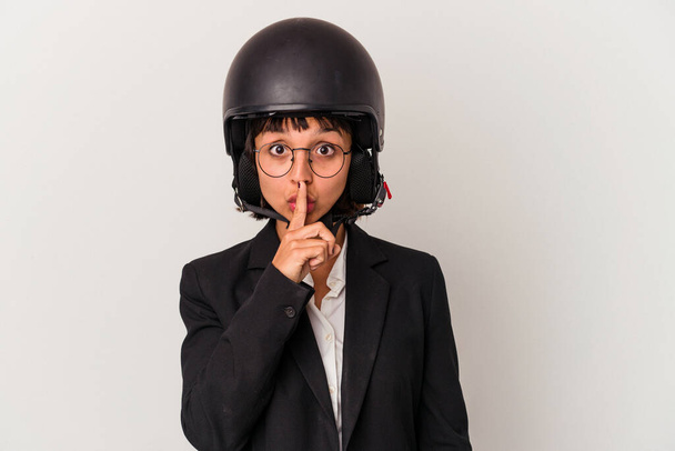Jovem mulher de negócios mista vestindo um capacete de moto isolado mantendo um segredo ou pedindo silêncio. - Foto, Imagem