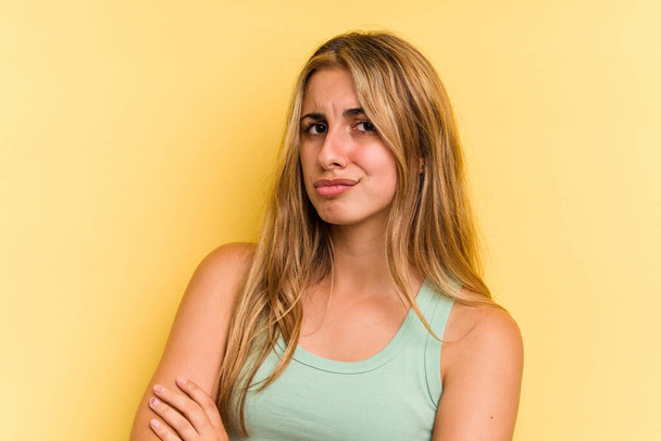 Young caucasian blonde woman isolated on yellow background  suspicious, uncertain, examining you. - Foto, Bild