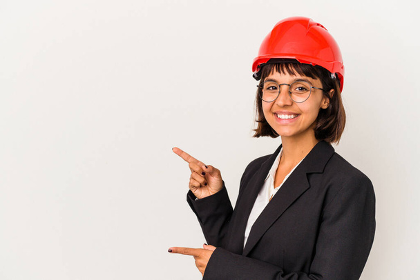 Mladý architekt žena s červenou přilbou izolované na bílém pozadí vzrušené ukazuje ukazováčky pryč. - Fotografie, Obrázek