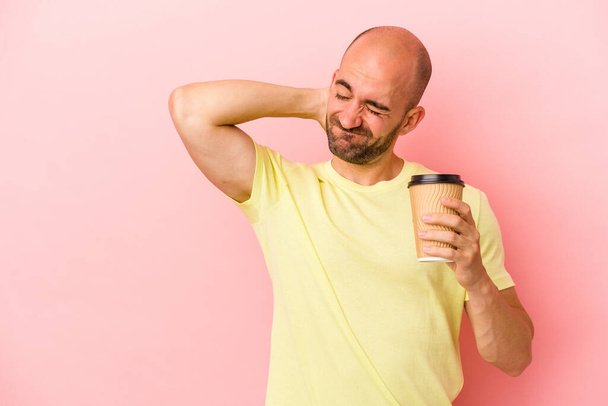 Young caucasian bald man holding a take away coffee isolated on pink background  touching back of head, thinking and making a choice. - Photo, Image