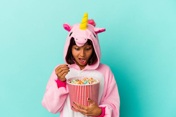 Mladá smíšená rasa žena nosí jednorožec pyžama jíst popcorn - Fotografie, Obrázek