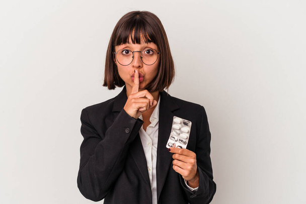 Молодая деловая женщина смешанной расы держит таблетки изолированы держать в секрете или просить тишины. - Фото, изображение