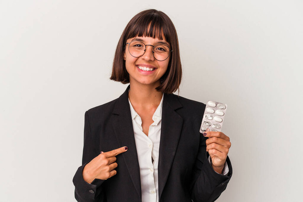 Jovem mulher de negócios mista segurando pílulas pessoa isolada apontando à mão para um espaço de cópia camisa, orgulhoso e confiante - Foto, Imagem